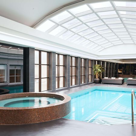 Stamford Plaza Melbourne Hotell Exteriör bild The photo shows an indoor swimming pool area. The pool is rectangular and has clear blue water, surrounded by a sleek, modern design. On one side, there is a round hot tub made of dark stone. Large windows line the walls, allowing natural light to fi
