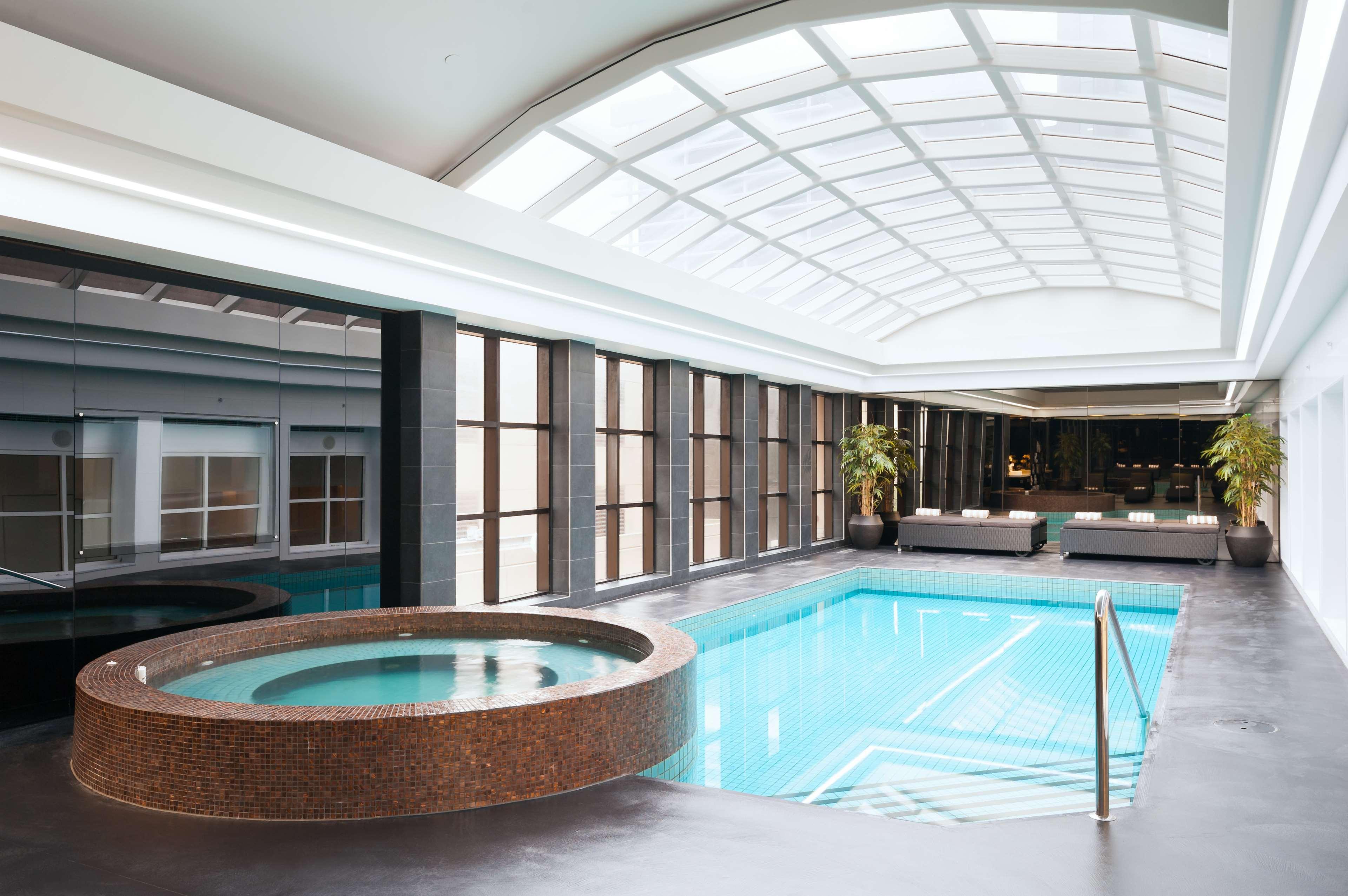 Stamford Plaza Melbourne Hotell Exteriör bild The photo shows an indoor swimming pool area. The pool is rectangular and has clear blue water, surrounded by a sleek, modern design. On one side, there is a round hot tub made of dark stone. Large windows line the walls, allowing natural light to fi