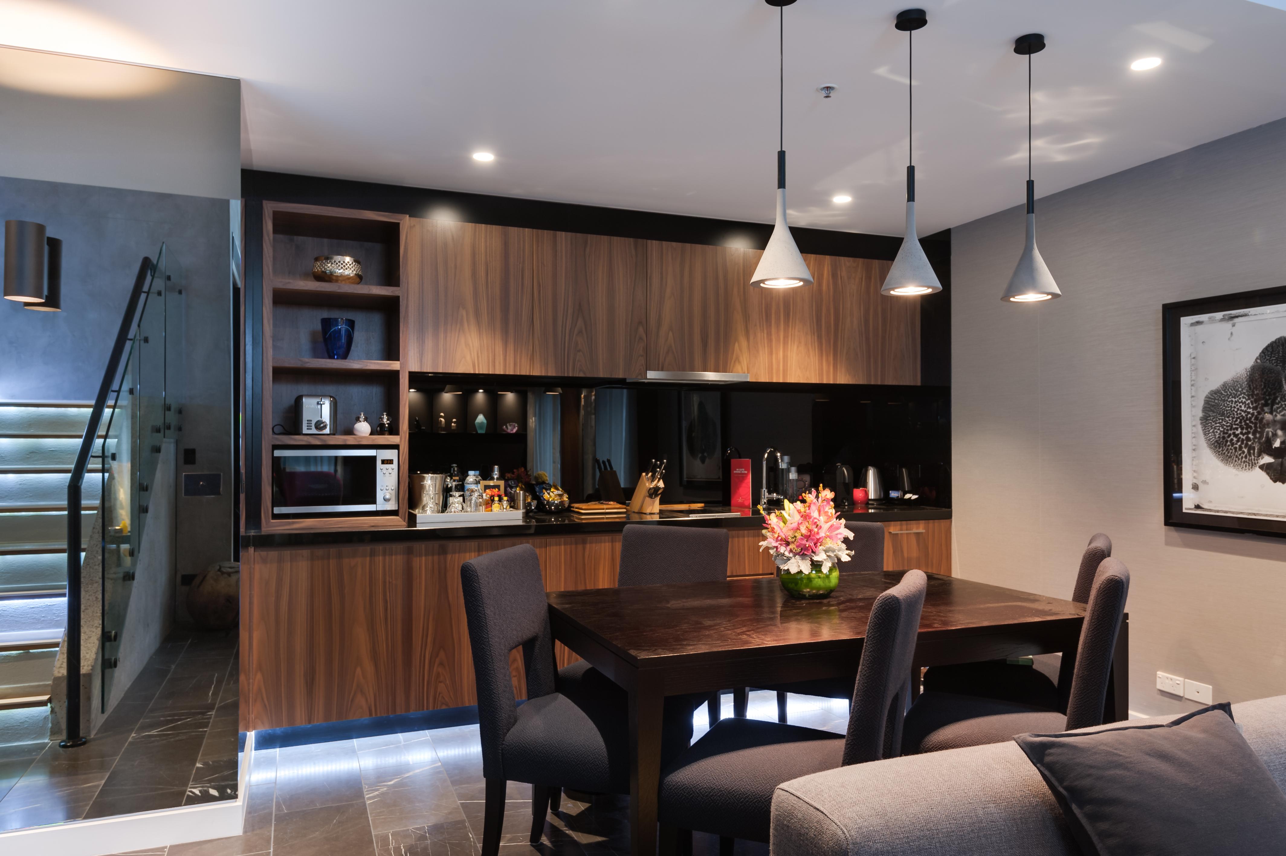 Stamford Plaza Melbourne Hotell Exteriör bild The image shows a modern kitchen and dining area. The kitchen features dark wooden cabinetry with black accents, a microwave, and various kitchen items arranged on the shelves. There is a dining table made of dark wood, surrounded by several chairs. 
