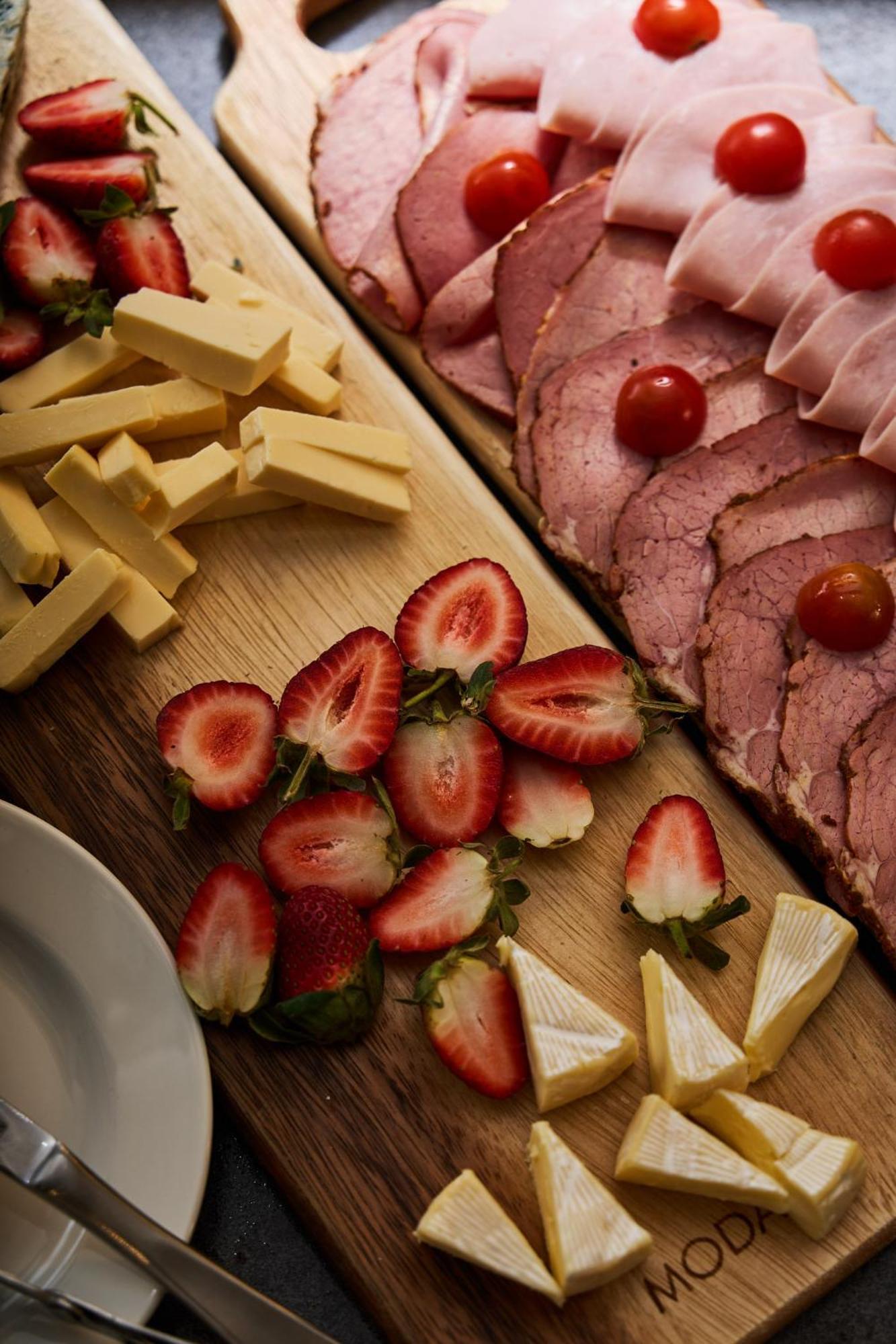 Stamford Plaza Melbourne Hotell Exteriör bild The photo displays an assortment of food items arranged on a wooden surface. There are slices of various meats, including ham, alongside round cherry tomatoes. Next to the meat, there are several pieces of yellow cheese cut into sticks. Additionally,